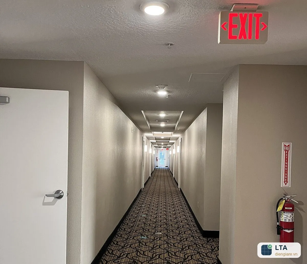 Hành lang tòa nhà có biển chỉ dẫn thoát nạn EXIT trên trần và bình chữa cháy treo tường